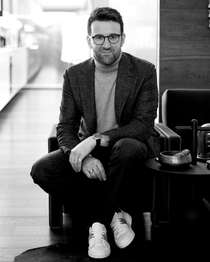 Carl Navè seated in a tweed jacket and turtleneck