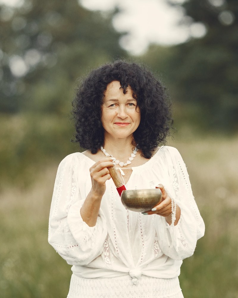 A practitioner in a meadow holding a bowl of broth