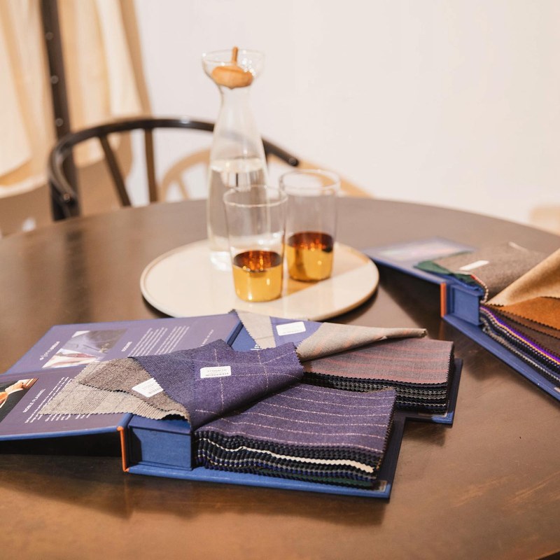 Open cloth books on the studio's round table, beside a carafe and two glasses