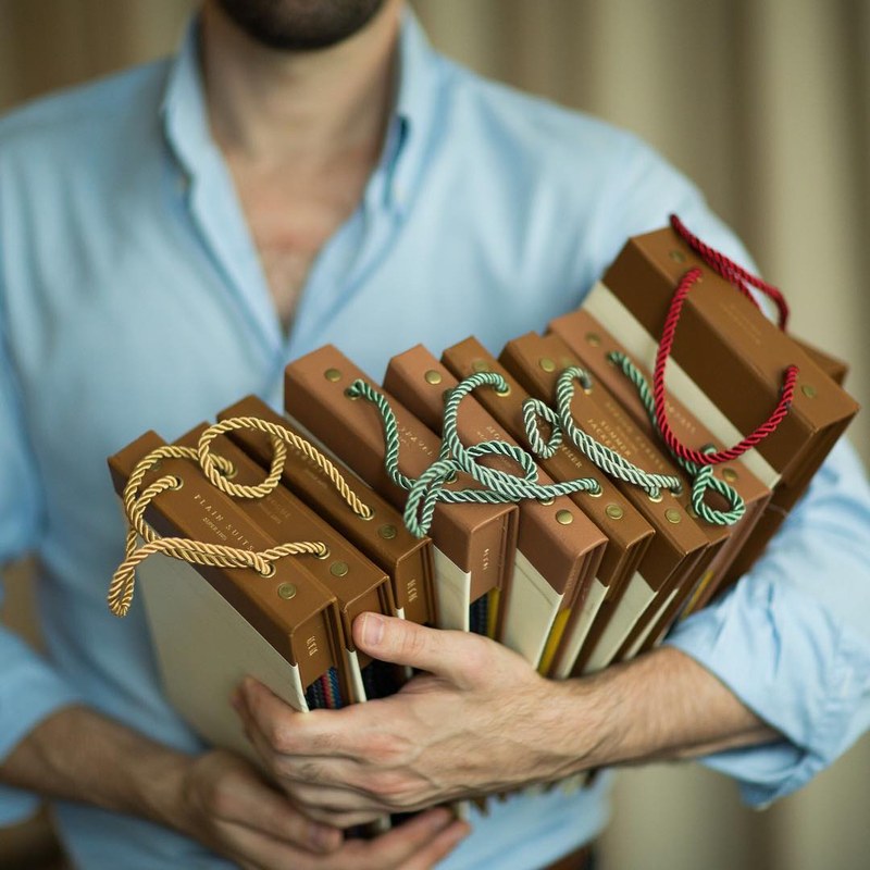 Carl holding an armful of cloth sample books tied with coloured cord